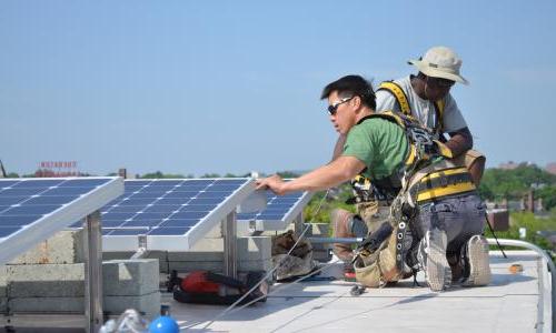 两名工人在屋顶上安装太阳能电池板